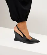 Zapato tipo slingback de color negro con acabado liso. Presenta punta fina, tira trasera ajustable con hebilla metálica y un diseño de taco anabela integrado a la suela.