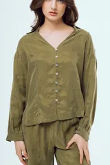 Camisa negra de manga larga con cuello en V, cierre frontal de botones y costuras decorativas en contraste de color blanco.