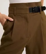 Short de sastrería negro, corte recto, con cintura alta, trabillas, pliegues frontales y detalle de medio cinturón con hebilla lateral.