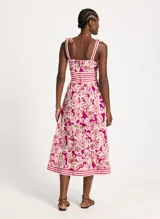 Falda midi con estampado floral en tonos fucsia y beige, con cintura alta y corte acampanado. Presenta una faja a rayas horizontales en la cintura y en el ruedo.