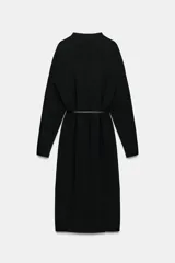 Vestido midi de punto color marrón oscuro, con cuello perkins y manga larga. Presenta un diseño holgado que se ajusta a la cintura mediante un cinturón fino de cuero sintético con hebilla metálica dorada.