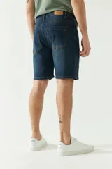 Bermuda de jean azul oscuro con bolsillos delanteros y traseros, cierre con cremallera y trabillas para cinturón.