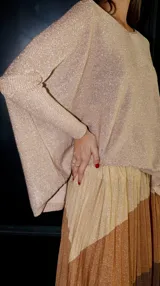 Pollera larga plisada con diseño de franjas horizontales en tonos marrón oscuro y beige brillante con lurex. Posee elástico en la cintura.