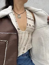 Campera tipo gamulán color marrón, con interior y detalles en corderito blanco. Presenta cierre frontal, cuello solapa y bolsillos laterales.