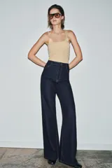 Jeans de tiro alto estilo wide leg, color marrón oscuro, con diseño de cinco bolsillos y cierre frontal de cremallera y botón metálico.