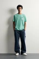 Camiseta regular fit de color verde, con cuello redondo, manga corta y un bolsillo de parche en el pecho con detalle de etiqueta estampada.