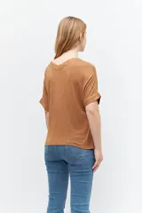 Remera marrón de tejido liso, con escote en V, mangas cortas y cierre frontal con botones.