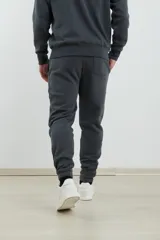 Pantalón jogging de corte ajustado, con cintura elástica y puños elastizados en los tobillos. Presenta un diseño minimalista en color gris oscuro, ideal para un look urbano y deportivo.