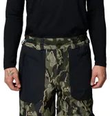 Pantalón técnico de esquí con tecnología impermeable y transpirable Omni-Tech. Presenta un diseño estampado de camuflaje en tonos verdes y negros, con paneles sólidos en negro. Incluye rodillas articuladas, ventilación en las piernas, cintura ajustable, bolsillos con cremallera y cremalleras en los puños para facilitar el uso con botas de nieve.