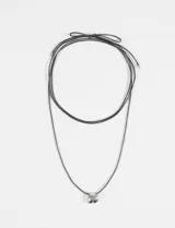 Collar largo de cordón negro ajustable con nudo corredizo y dije metálico de forma irregular en color plateado.