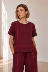 Blusa de lino color bordó con cuello redondo, mangas cortas y costuras decorativas con bordado en color naranja.