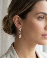 Aros tipo argolla de plata con dije colgante en forma de serpiente, decorados con circonias brillantes y detalles en negro en los ojos.