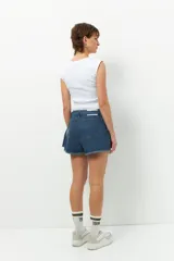 Short pollera de jean prelavado color negro, con lazo en uno de sus laterales y detalle de flecos en las terminaciones.