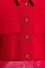 Vestido rojo de corte recto, tipo camisa, con cuello solapa, manga corta y botones metálicos frontales. Presenta dos falsos bolsillos con solapa en el pecho y un cinturón ancho en tono rojo brillante.