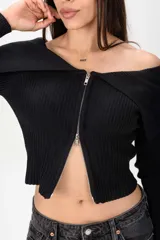 Sweater corto de tejido acanalado en color bordó, con cuello tipo off-shoulder solapado y cierre frontal completo con cremallera.
