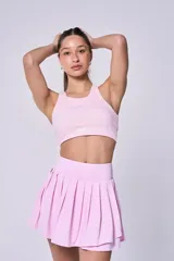 Conjunto deportivo compuesto por un top de cuello redondo y una pollera tableada con cintura alta, ambos en color rosa pastel.