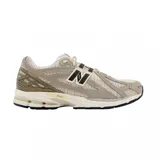 Championes urbanos New Balance modelo 1906R, color beige con detalles en marrón oscuro y blanco. Presentan una estructura técnica de malla y paneles sintéticos, con el logo N característico en los laterales y entresuela con tecnología N-ergy.