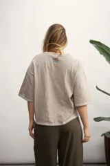 Remera color crema de corte holgado, con mangas cortas y costuras a la vista en color ocre.