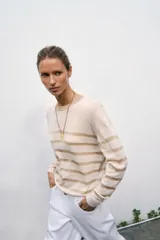 Jersey de punto de cuello redondo y manga larga, con diseño de rayas horizontales en tono metalizado sobre base color crema.