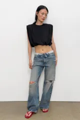Top de algodón con cuello redondo, diseño sin mangas con hombreras marcadas y detalle de pliegues. Presenta un bajo acabado tipo globo con elástico.