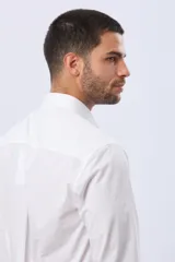 Camisa de vestir blanca entallada, de manga larga, cuello camisero y cierre frontal de botones, con elastano añadido para mayor confort.