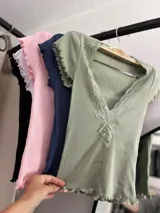 Remera corta de color verde claro con detalles de encaje en el escote y mangas cortas.