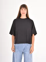 Remera de corte boxy y holgado, con cuello redondo y mangas cortas, en color negro liso.