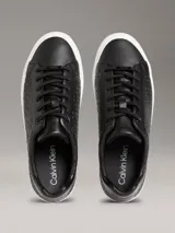 Zapatillas negras de piel sintética con monograma de Calvin Klein grabado en relieve, suela de goma blanca y cordones al tono.