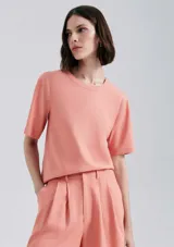 Blusa manga corta de tejido liso, color salmón, con cuello redondo y corte recto.