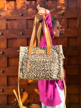 Cartera tipo tote bag con estampado animal print, doble asa de mano color cuero y correa larga desmontable y regulable.