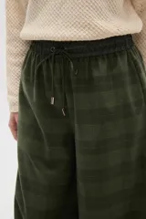 Pantalon de corte ancho y tiro alto, confeccionado en tela con estampado a cuadros en tonos verdes. Presenta cintura elástica con cordón de ajuste frontal.