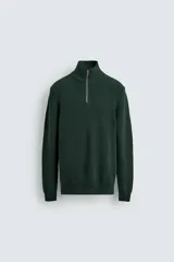 Jersey de punto perlado en color verde oscuro, con cuello perkins y cierre frontal de cremallera. Presenta manga larga y acabados en rib en puños y bajo.