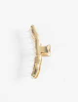 Broche para el pelo tipo clip de diseño irregular con acabado metálico brillante en tono dorado.