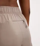 Bermuda deportiva Get Over modelo runner color beige, con cintura elástica, bajo redondeado y aberturas laterales. Cuenta con un pequeño bolsillo funcional trasero.