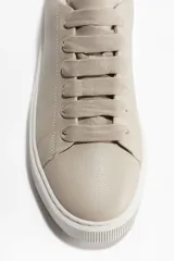 Zapatillas deportivas color beige con suela gruesa acanalada.