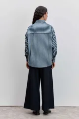 Camisa de manga larga a rayas verticales azul marino y blancas, con cuello clásico, bolsillo de parche en el pecho y ribetes finos en color rojo.