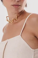 Gargantilla dorada con cadena fina y dije rígido con forma de onda.