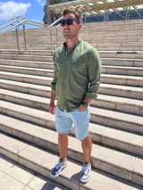 Camisa verde oliva de lino con cuello mao, manga larga y abotonadura frontal.