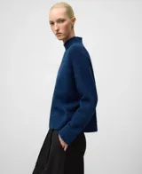 Sweater de punto en color tostado con cuello chimenea y mangas raglán, confeccionado en una mezcla de lana merino y alpaca que le otorga una textura suave y abrigada.