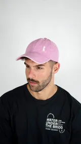 Gorra de gabardina color rosado con efecto gastado, visera curva y bordado pequeño en el frente.