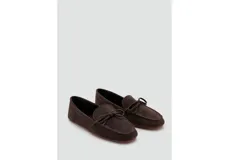 Mocasines de gamuza color marrón oscuro, con detalle de lazo en el empeine y suela plana.