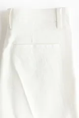 Jeans de denim blanco off-white, de tiro alto y corte acampanado con botamanga ancha y raya marcada al frente.