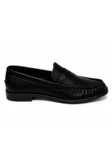 Mocasín de símil cuero negro con silueta clásica, costuras marcadas y tira sobre el empeine.