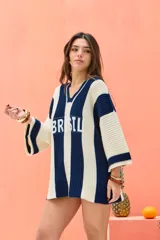 Remerón tejido de punto oversize, con diseño de rayas verticales en colores crudo y azul marino. Cuenta con escote en V y la palabra "BRASIL" estampada en el frente.