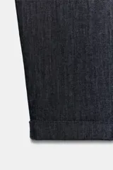Pantalón chino de tiro medio en color azul oscuro, con bolsillos frontales, falsos bolsillos de vivo en la espalda y bajo con vuelta. Incluye un cinturón trenzado de color marrón.