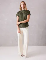 Blusa de cuello redondo y manga corta, completamente cubierta de lentejuelas en color marrón oscuro. Presenta un diseño de corte recto y forro interno a tono.