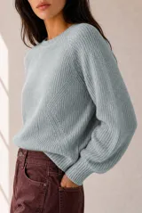 Buzo de tejido de punto color celeste, con cuello redondo, mangas largas abullonadas y puños ajustados.