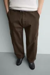 Pantalón cargo de corte relajado confeccionado en tejido de algodón con elasticidad. Presenta bolsillos laterales tipo cargo con solapa en las perneras, bolsillos frontales y bolsillos traseros de doble vivo. Cierre frontal con cremallera y botón.