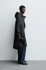 Parka de tejido con acabado engomado, diseño de corte recto y largo medio. Presenta cuello subido con capucha ajustable, cierre frontal con cremallera oculta bajo solapa con botones a presión, mangas largas y bolsillos laterales de vivo.