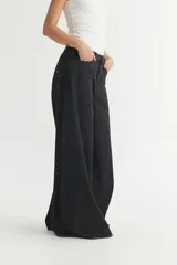 Pantalón jean negro de pierna ancha, corte holgado y tiro medio.